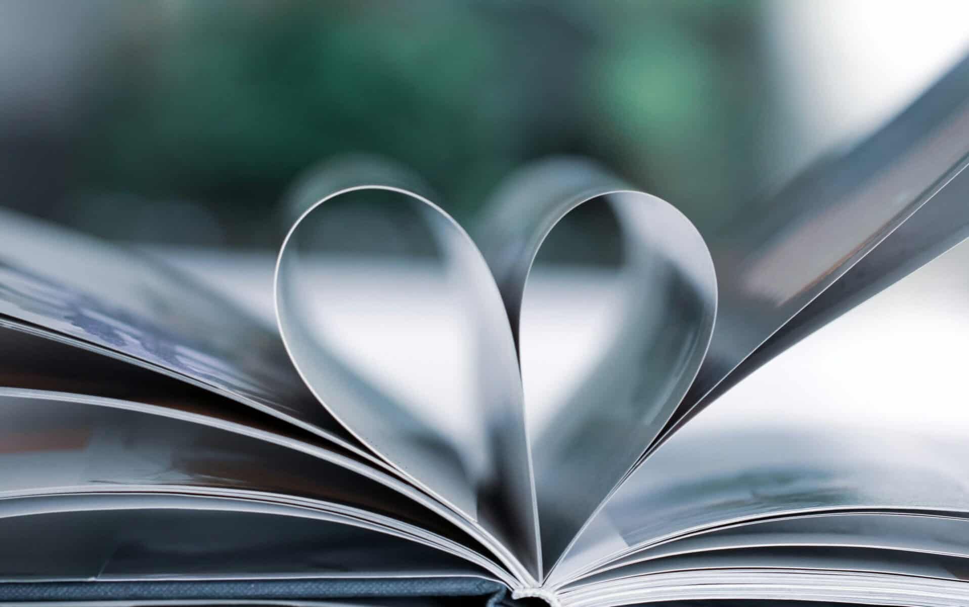 An up-close shot of a book laid open on a flat surface. Two of the middle pages are folded inwards meeting in the middle - it makes a heart shape. It represents grief and love to match this blog post.