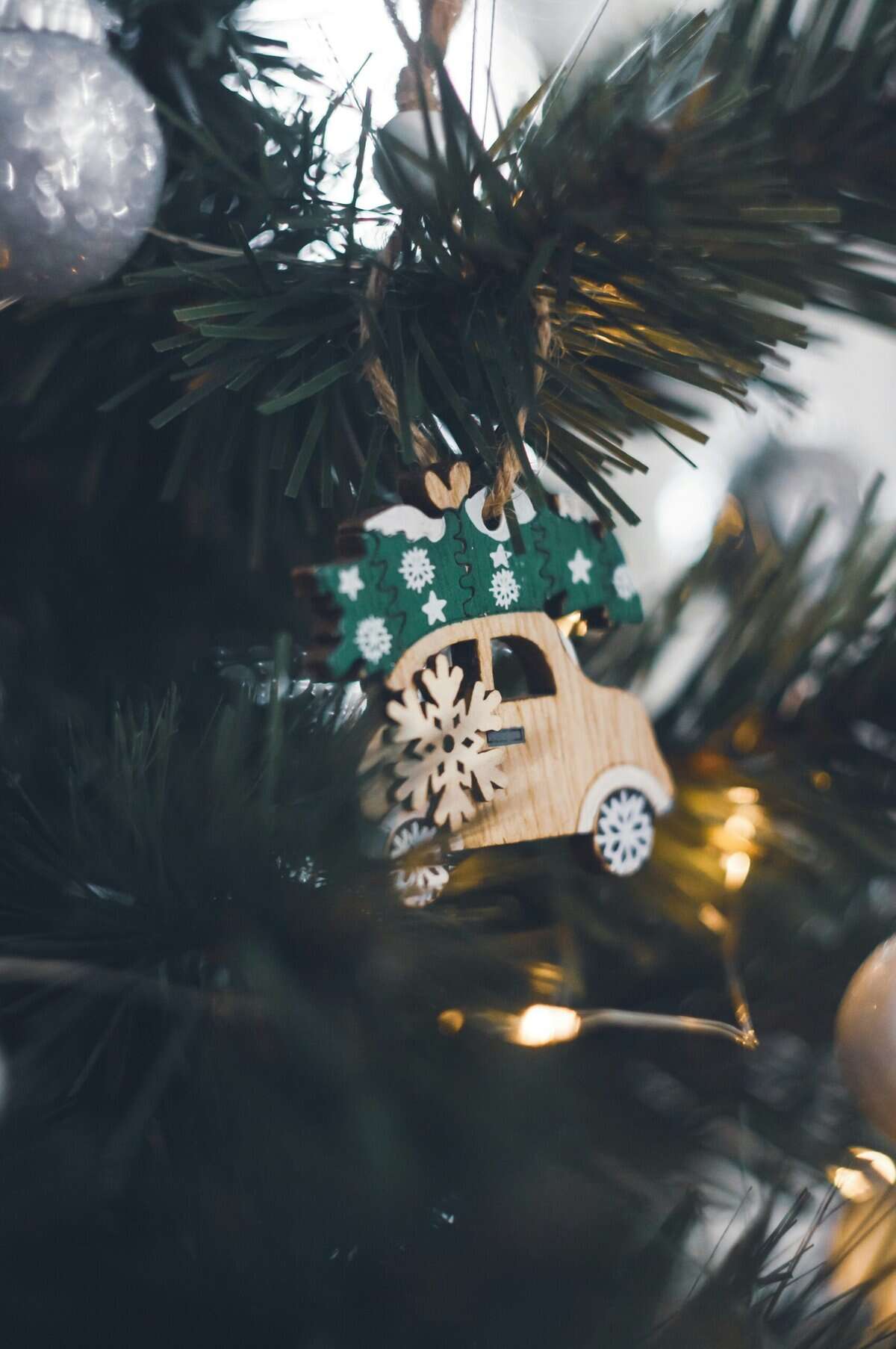 Dimly lit close up of a christmas tree with a small wooden deocration of a car. This represents the theme of the blog -Holiday Stress and Mental Health: Why the Season Can Feel Overwhelming